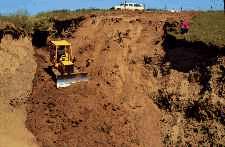Crawler tractor forming a firm bed for a pipe drop structure.